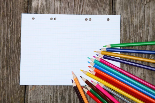 Checkered sheet and pencils on the wooden background — Stock Photo, Image