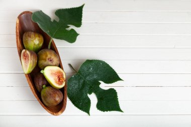 Tahta bir tabakta incir ve arka planda yapraklar..