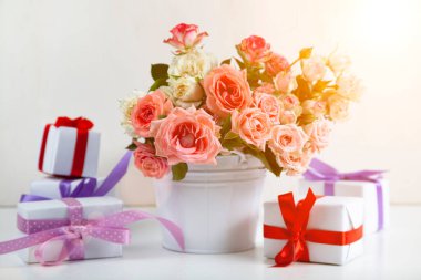 Açık ahşap arka planda hediyeli pembe güller ve kutular..