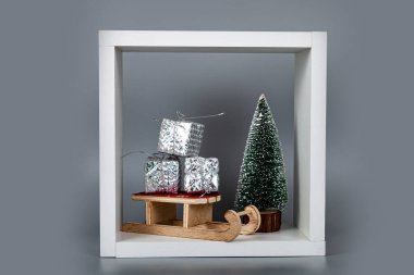 Kızakta hediyeler ve beyaz küpte bir Noel ağacı. Noel şenliği arka planı.