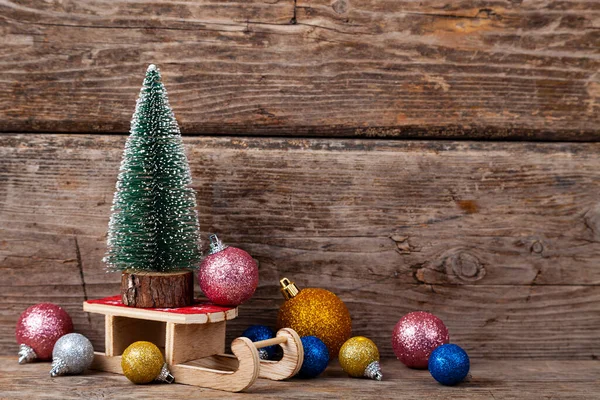 圣诞树在雪橇上 球在木制背景上 节日明信片 — 图库照片