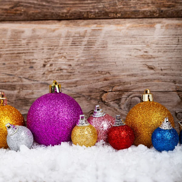 クリスマスのお祝いの背景 古い木の背景に雪の中のクリスマスボール — ストック写真