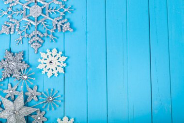 Mavi ahşap arka planda beyaz ve gümüş Noel taneleri. Noel kartı. Metnin için yer.