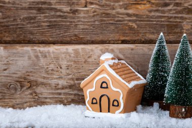 Zencefilli kurabiye evi ve eski ahşap arka planda karda Noel ağaçları. Yeni yıl kartı.