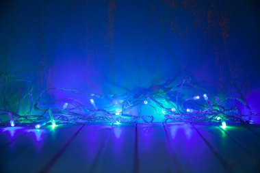 Çok renkli bir çelenk karanlıkta parlar. Işıklı Noel arkaplanı.