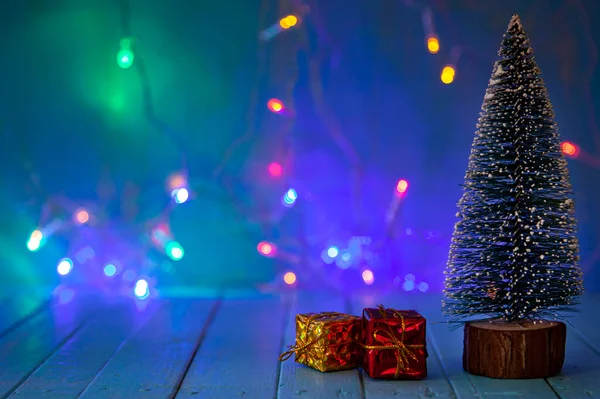 圣诞树和圣诞灯背景下的礼物 节日明信片 — 图库照片