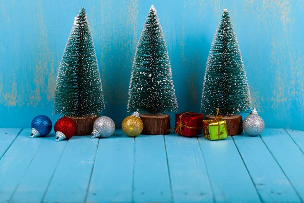 三棵圣诞树蓝色背景上的礼物和球圣诞贺卡 — 图库照片