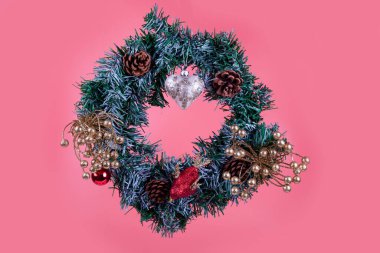 Pembe arka planda kalbi olan bir Noel çelengi. Noel dekoru.