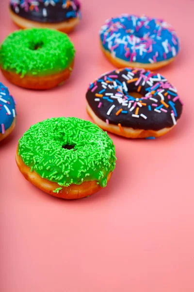粉色背景上美味的彩色甜甜圈 — 图库照片