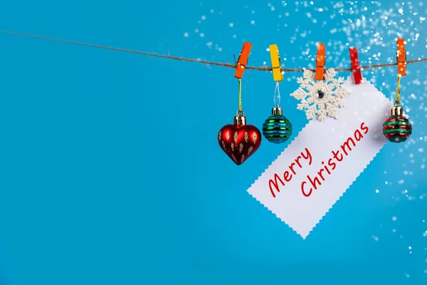 圣诞装饰品挂在蓝色背景的绳子上 把你的文字放好 圣诞贺卡 — 图库照片