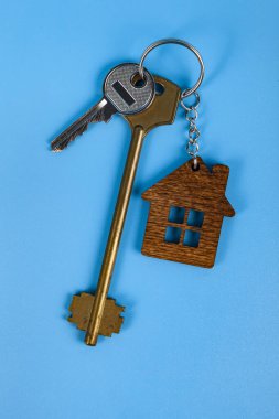 Keys with a keychain in the form of a house.  Rent apartments, Real Estate and buying a house idea. Blue background