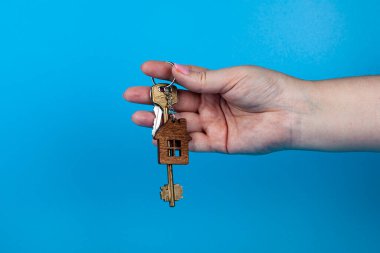 Rent apartments, Real Estate and buying a house idea. Blue background. Hand with keys.