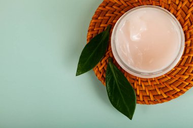 SPA natural organic cosmetics for personal hygiene. Skin cream and oil in cosmetic bottles, green leaf on rattan container in bathroom.