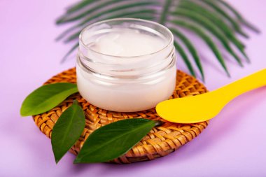 SPA natural organic cosmetics for personal hygiene. Skin cream and oil in cosmetic bottles, green leaf on rattan container in bathroom.Lilac background.