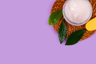 SPA natural organic cosmetics for personal hygiene. Skin cream and oil in cosmetic bottles, green leaf on rattan container in bathroom.Lilac background.