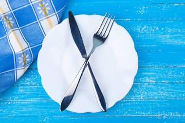 Çatal bıçak ve çatal takımı, beyaz tatlı tabağı, mavi arka plan, düz zemin, telif alanı