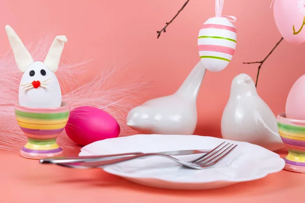 イースターテーブルの設定とお祝いの装飾 白い鳥と多色の卵と夕食 ピンクの背景 閉じろ — ストック写真