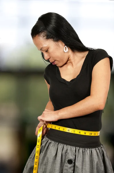 Mulher hispânica medindo sua cintura — Fotografia de Stock