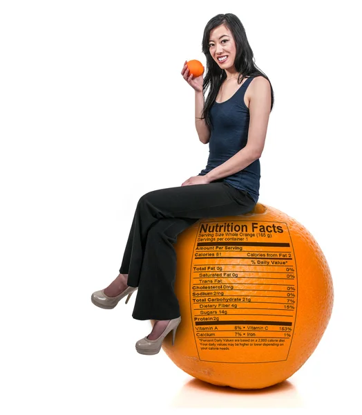 Mujer sentada en naranja con etiqueta nutricional — Stockfoto