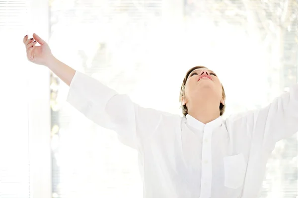 Relaxed young woman at home with raised arms — Stock Photo, Image