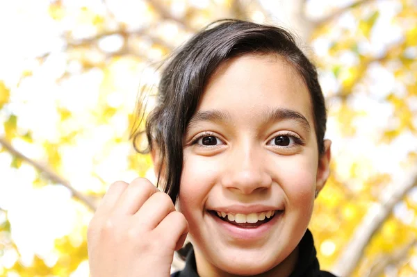 Happy kid and autumn leaves in a park — Stock Photo, Image