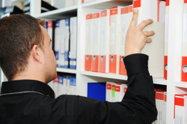 klasörler, birlikte raflarda koyarak ofisinde çalışan adam