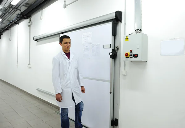 Joven trabajador abriendo puerta de refrigerador industrial — Foto de Stock