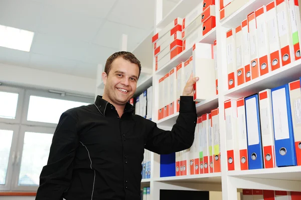 Man aan het werk op kantoor samenstellen van mappen op de planken — Stockfoto