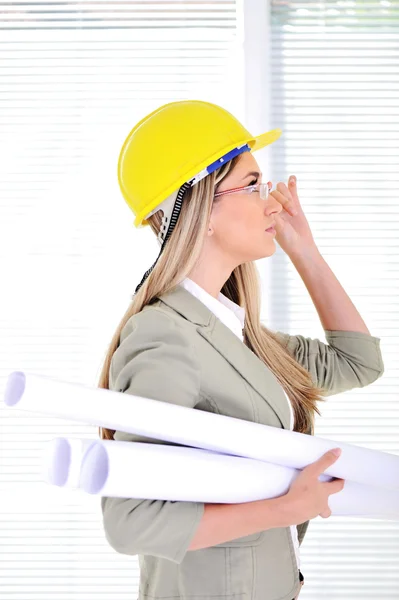Ingegnere donna con casco e cianografie in ufficio — Foto Stock