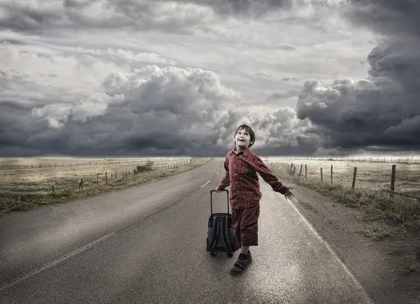 Kleine school met zijn zak jongen lopen op de lege weg — Stockfoto