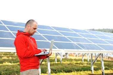erkek mühendis dizüstü, güneş panelleri arka planı olarak kullanma