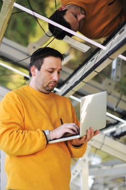 dizüstü bilgisayar kullanan ve iş yerinde, telleri bağlarken mühendis