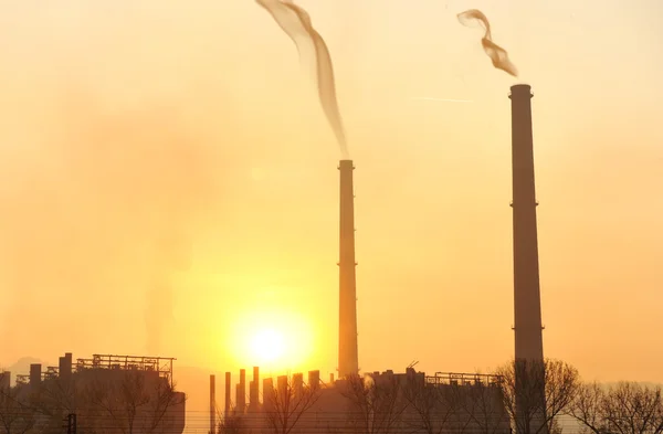 Teollisuus, iso savupiippu auringonlaskun aikaan — kuvapankkivalokuva