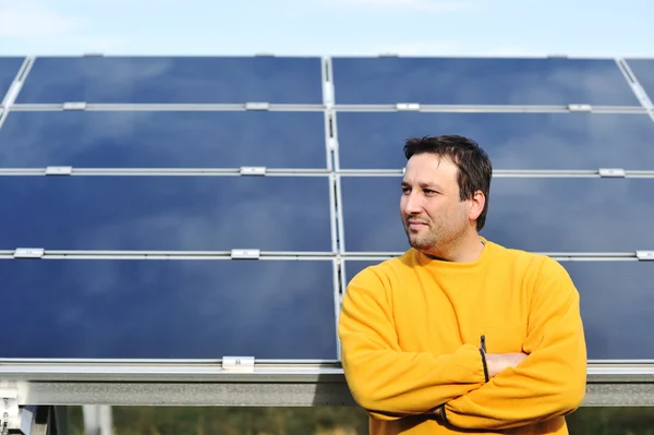 Jovem trabalhador do sexo masculino com painéis solares no fundo — Fotografia de Stock
