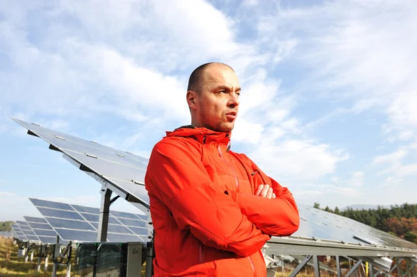 Jonge mannelijke ingenieur met zonnepanelen op achtergrond — Stockfoto