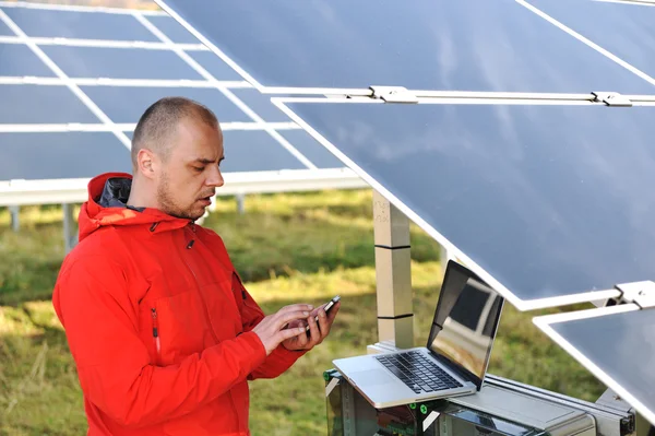 Engineer working with laptop by solar panels, talking on cell phone — Stock Photo, Image