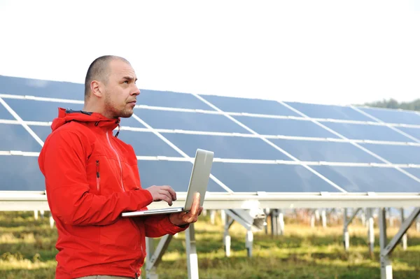 Manliga ingenjör med laptop, solpaneler i bakgrunden — Stockfoto