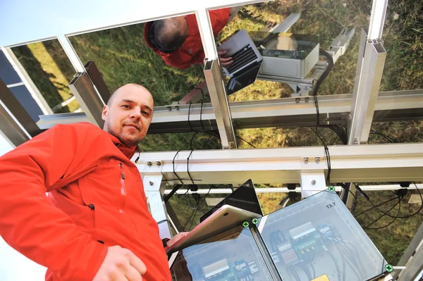 Ingeniero que trabaja con el ordenador portátil de fijación de paneles solares Imágenes de stock libres de derechos