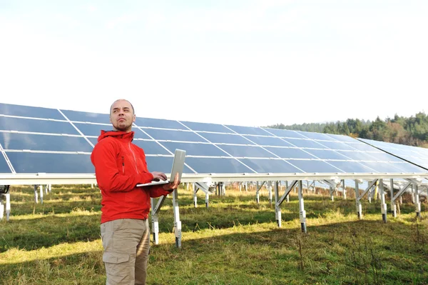 ラップトップは、バック グラウンドでの太陽電池パネルを使用する男性の技術者 ストック写真