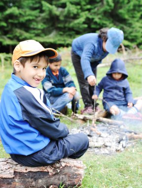 Barbekü doğada, grup çocuk sosis ateşe hazırlanıyor