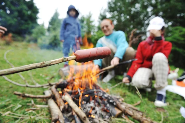 Grill w przyrodzie, Grupa przygotowania kiełbasy na ogień (Uwaga: wybranego ostrości) — Zdjęcie stockowe