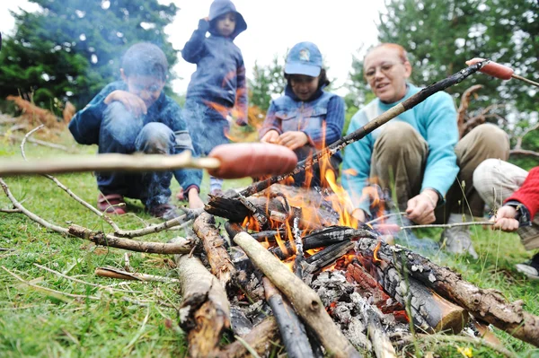 Barbecue in de natuur, groep voor te bereiden worstjes op brand (Opmerking: geselecteerd focus) — Stockfoto