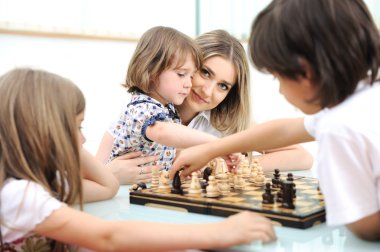 mutlu bir aile evde çocukları ile satranç oynayan genç anne