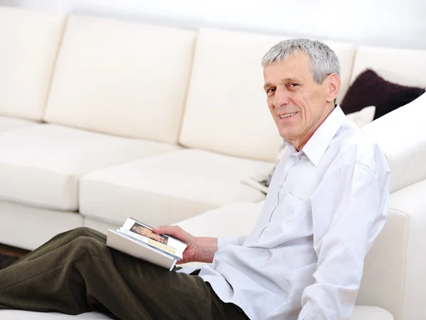 Oudere man ontspannen, lezen van boek in woonkamer — Stockfoto