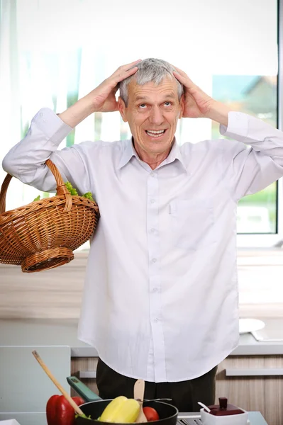 Good looking elderly man cooking in kitchen — Stock Photo, Image