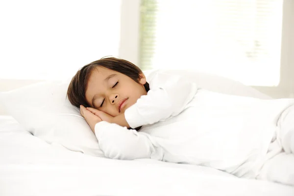 Chlapče, na spaní postele, happy spaním v bílé ložnici — Stock fotografie