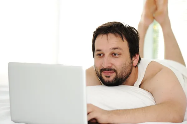 Hombre en la cama de dormir usando el ordenador portátil —  Fotos de Stock
