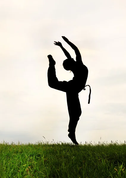 Sport acrobatic girl against gray sky — Stock Photo, Image