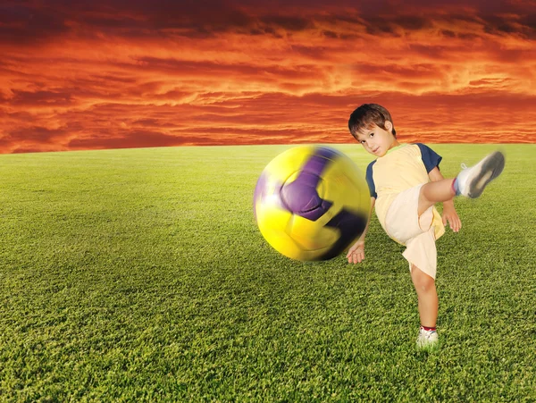 Boy hit the ball on the green grass — Stock Photo, Image