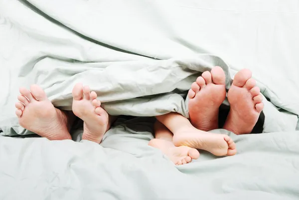 Feliz família na cama debaixo do lençol — Fotografia de Stock